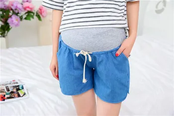 Tehotné ženy s brušnej tenké uvoľnene denim šortky. Tehotné ženy nosia džínsy nadol. Materstva. Doprava zadarmo